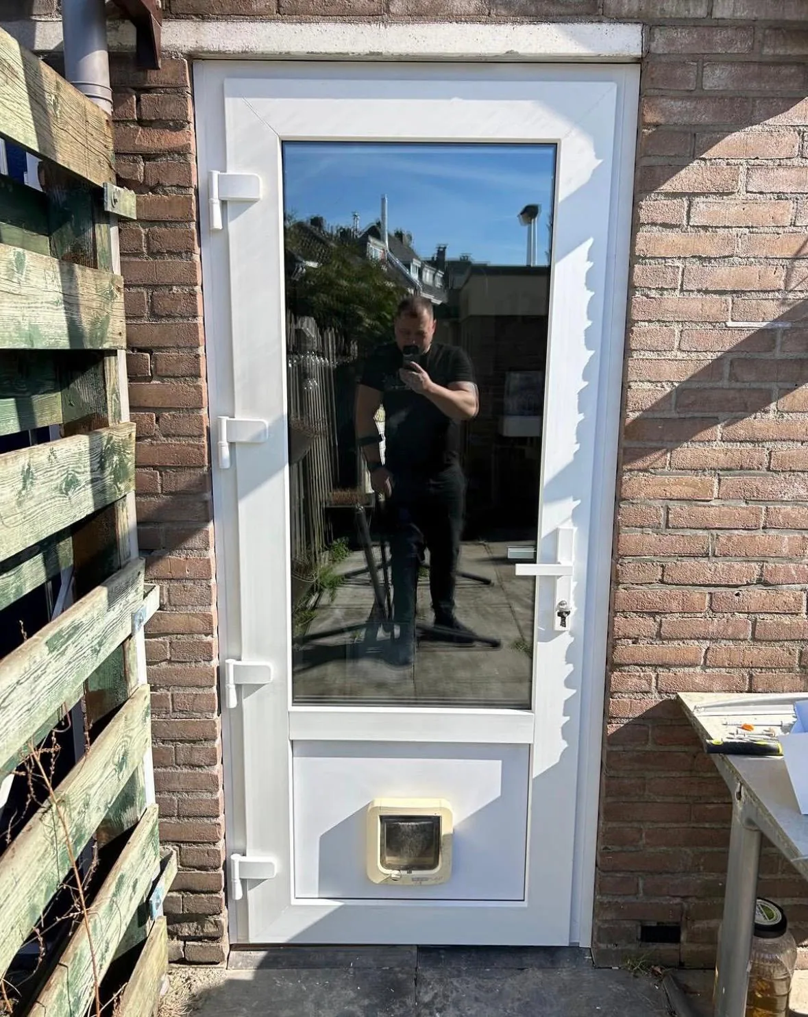 Witte achterdeur met glas en kattenluik na plaatsing