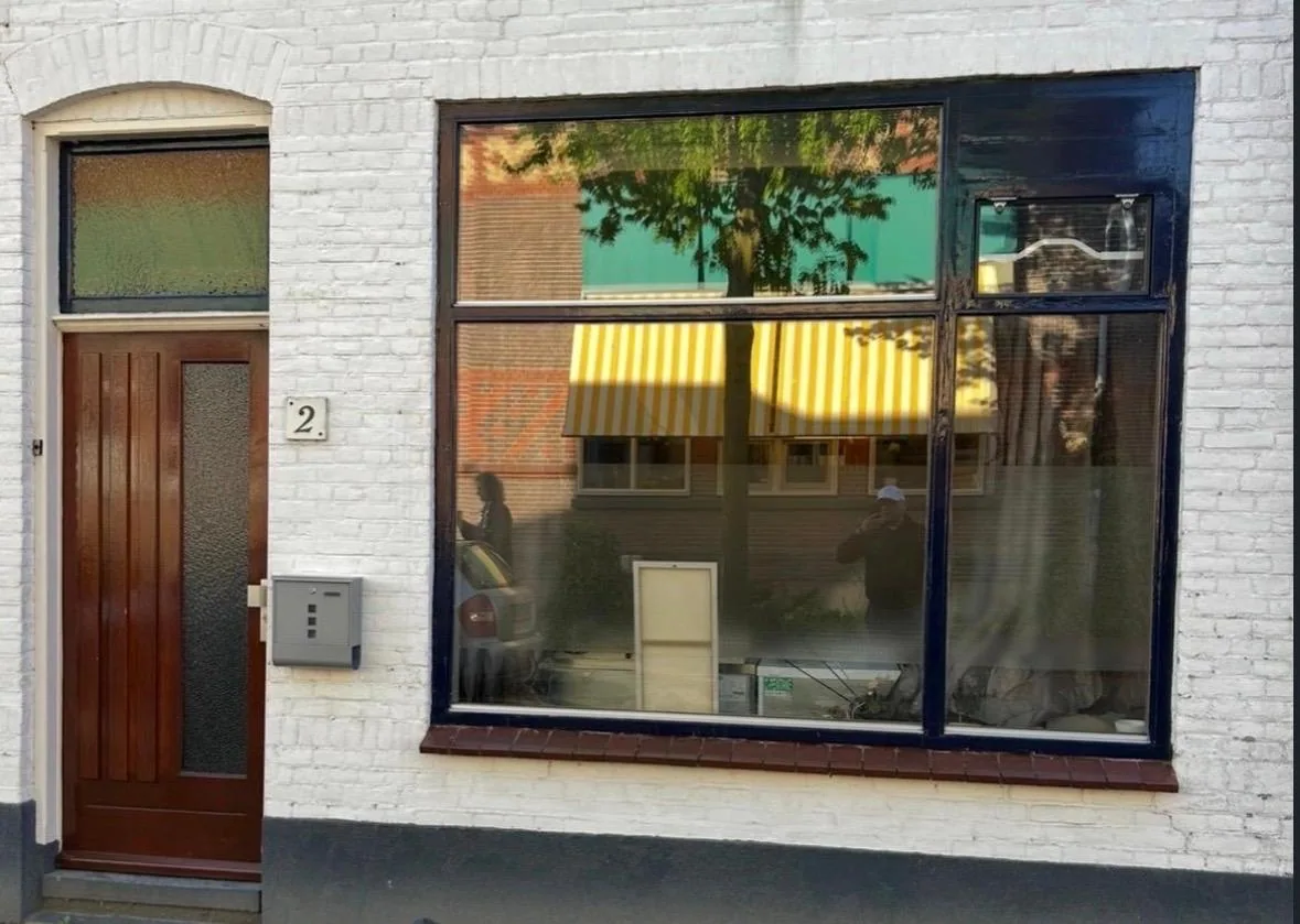 Oude deur en raampartij in witte gevel voor vervanging